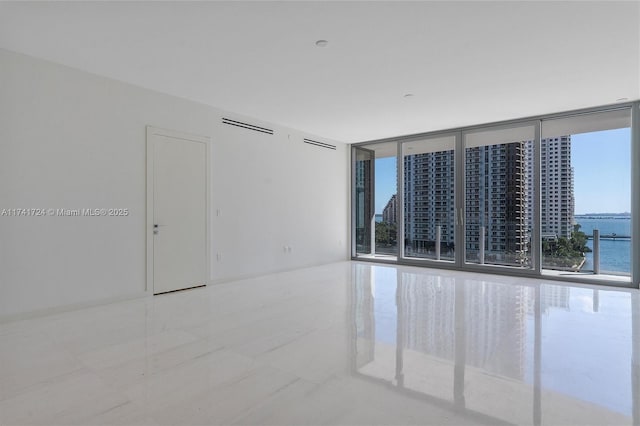 empty room featuring a water view and floor to ceiling windows