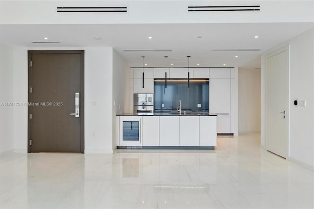 kitchen with wine cooler, fridge, double oven, pendant lighting, and white cabinets