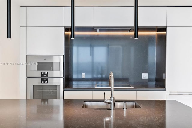 kitchen featuring stainless steel double oven, sink, and white cabinets