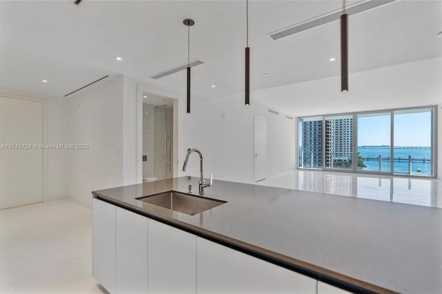 kitchen with a water view, sink, white cabinets, and decorative light fixtures