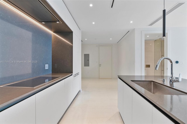 kitchen with sink, black electric stovetop, white cabinets, and electric panel