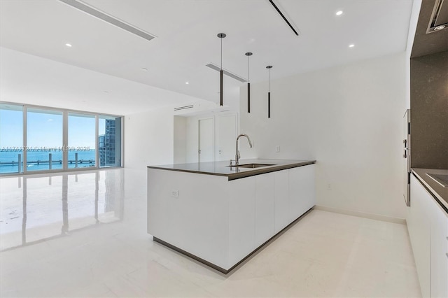 kitchen featuring a water view, pendant lighting, sink, and white cabinets