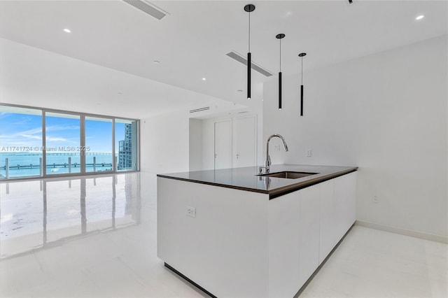 kitchen featuring sink, white cabinetry, floor to ceiling windows, a water view, and decorative light fixtures