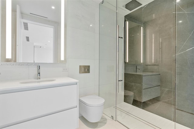 bathroom with vanity, tile walls, toilet, and a tile shower