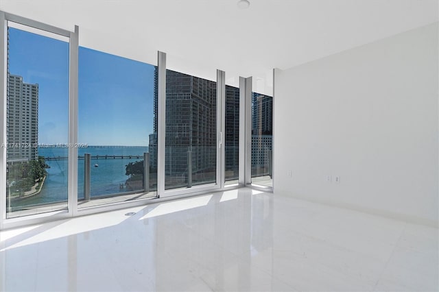 unfurnished room featuring expansive windows and a water view