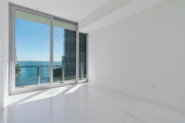 unfurnished room with floor to ceiling windows and a water view