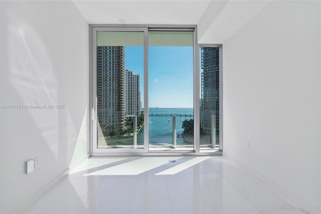 spare room with a water view and a wall of windows