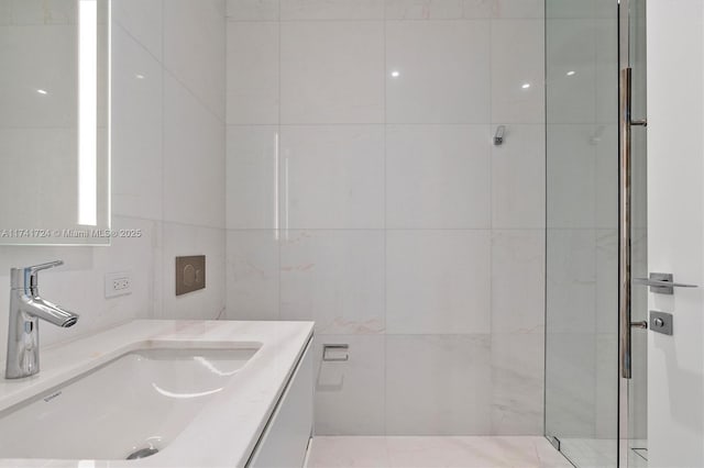 bathroom with vanity, an enclosed shower, and tile walls