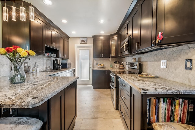 kitchen with a breakfast bar, appliances with stainless steel finishes, hanging light fixtures, dark brown cabinetry, and light stone counters