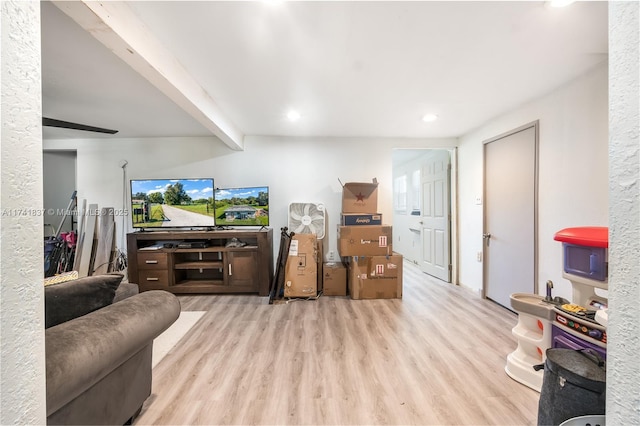 living room with beamed ceiling and light wood-type flooring