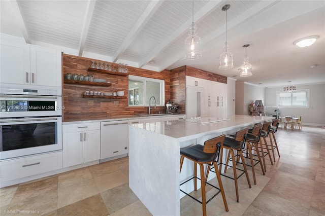 kitchen featuring white appliances, a center island, hanging light fixtures, and white cabinets