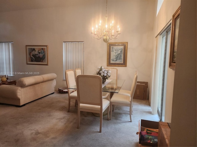 dining room featuring a high ceiling, a chandelier, and light colored carpet