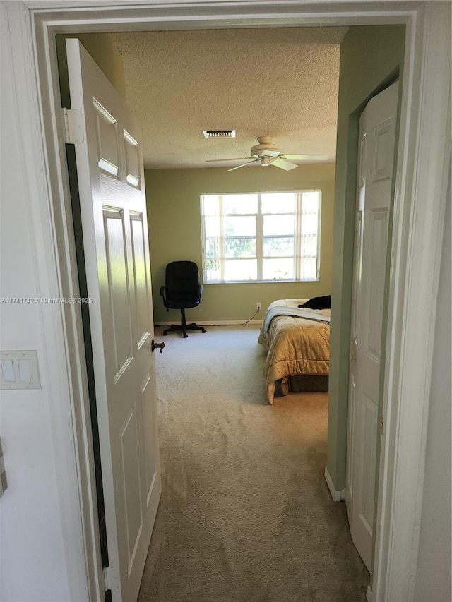 carpeted bedroom featuring a ceiling fan, baseboards, visible vents, and a textured ceiling