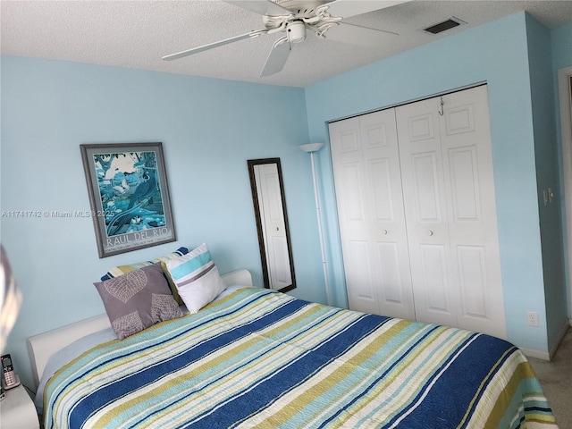 carpeted bedroom featuring a textured ceiling, ceiling fan, a closet, and visible vents