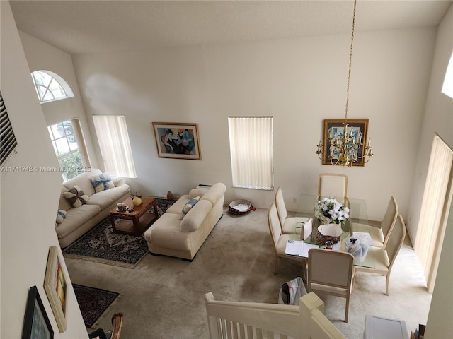 living room with carpet, a towering ceiling, and an inviting chandelier