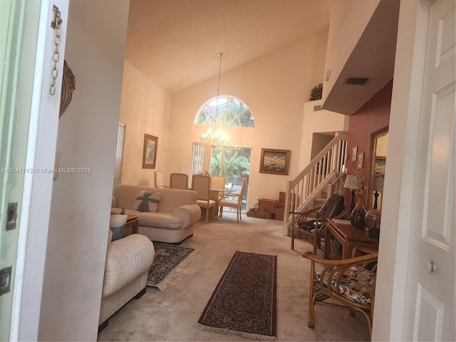 living area with high vaulted ceiling, light colored carpet, a notable chandelier, visible vents, and stairs