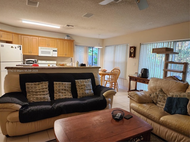 living room featuring light tile patterned floors, a wealth of natural light, visible vents, and a ceiling fan