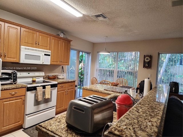 kitchen with light stone counters, white appliances, visible vents, and decorative light fixtures