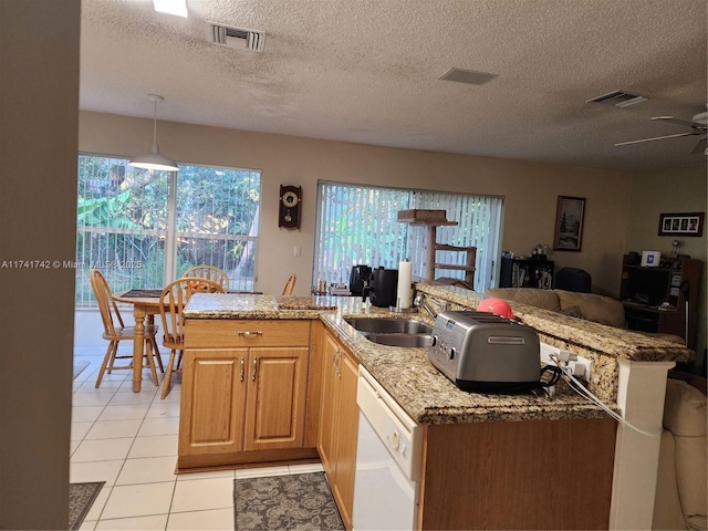 kitchen featuring pendant lighting, light tile patterned floors, visible vents, white dishwasher, and a sink