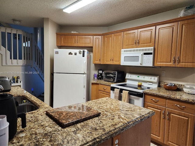 kitchen with white appliances, light stone counters, and brown cabinets