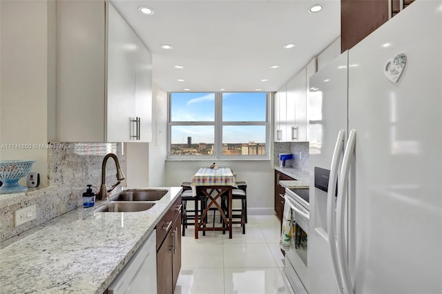 1833 S Ocean Dr Unit 1612, Hallandale Beach, FL 33009 - kitchen with white appliances, light tile patterned floors, decorative backsplash, light stone countertops, and a sink