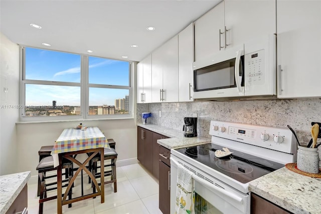 1833 S Ocean Dr Unit 1612, Hallandale Beach, FL 33009 - kitchen with white appliances, light stone countertops, white cabinetry, and decorative backsplash