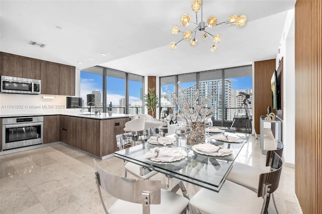 dining area featuring a notable chandelier, floor to ceiling windows, visible vents, and a city view