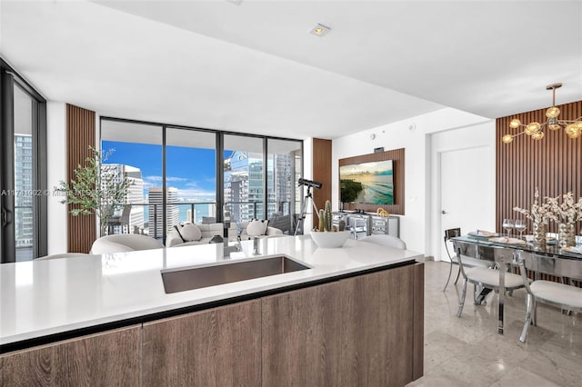 kitchen featuring a sink, light countertops, a notable chandelier, and decorative light fixtures