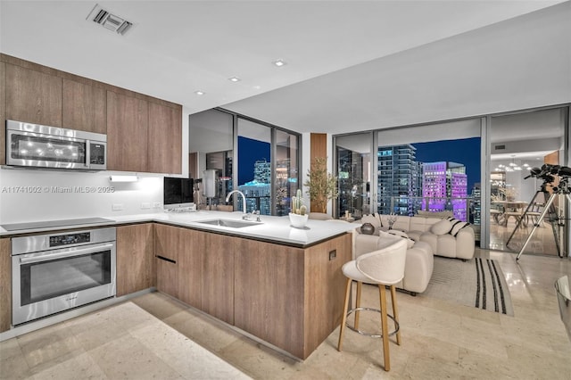 kitchen with stainless steel appliances, visible vents, a sink, modern cabinets, and a peninsula