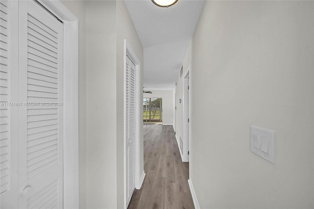 corridor with wood-type flooring and a textured ceiling