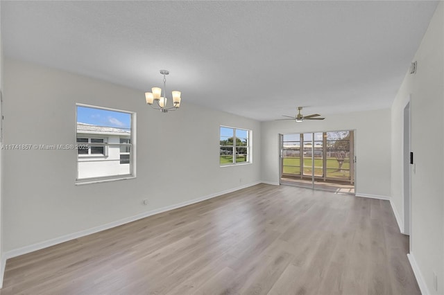 spare room with ceiling fan with notable chandelier, a textured ceiling, and light hardwood / wood-style floors