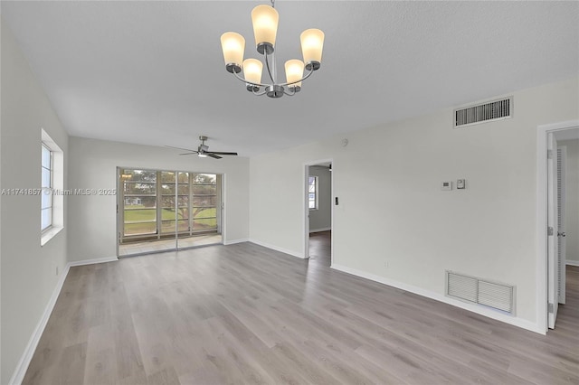 unfurnished living room featuring ceiling fan with notable chandelier, a textured ceiling, and light wood-type flooring