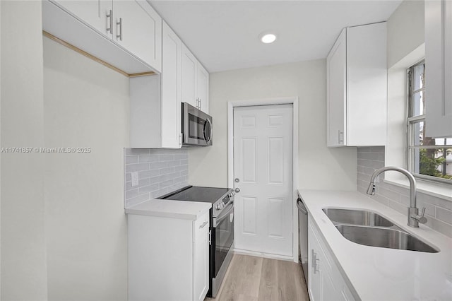 kitchen featuring light wood-type flooring, appliances with stainless steel finishes, sink, and white cabinets