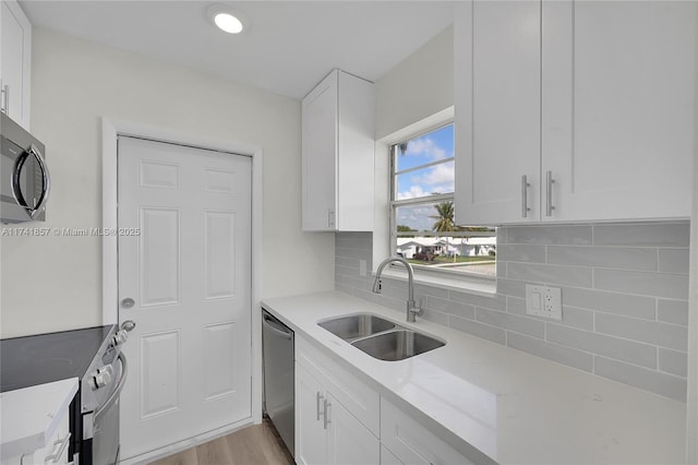 kitchen with light stone counters, appliances with stainless steel finishes, sink, and white cabinets