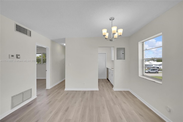 unfurnished room featuring a healthy amount of sunlight, light hardwood / wood-style flooring, and a textured ceiling