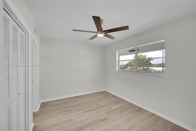 unfurnished bedroom featuring ceiling fan, a textured ceiling, light hardwood / wood-style floors, and a closet