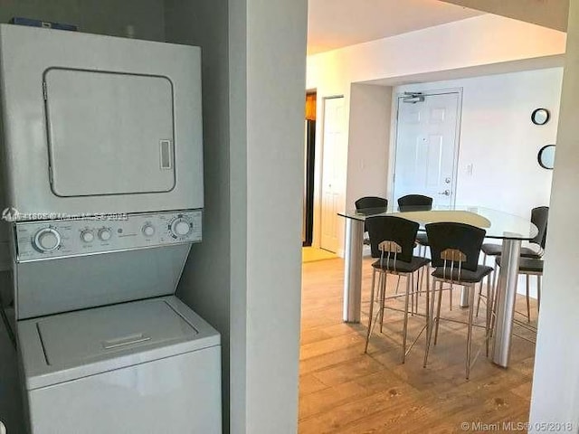 laundry room with stacked washer / dryer and light wood-type flooring