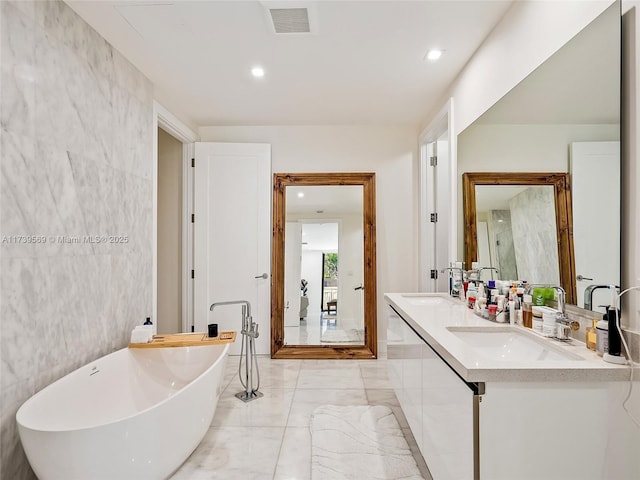 bathroom with vanity, a tub, and tile walls