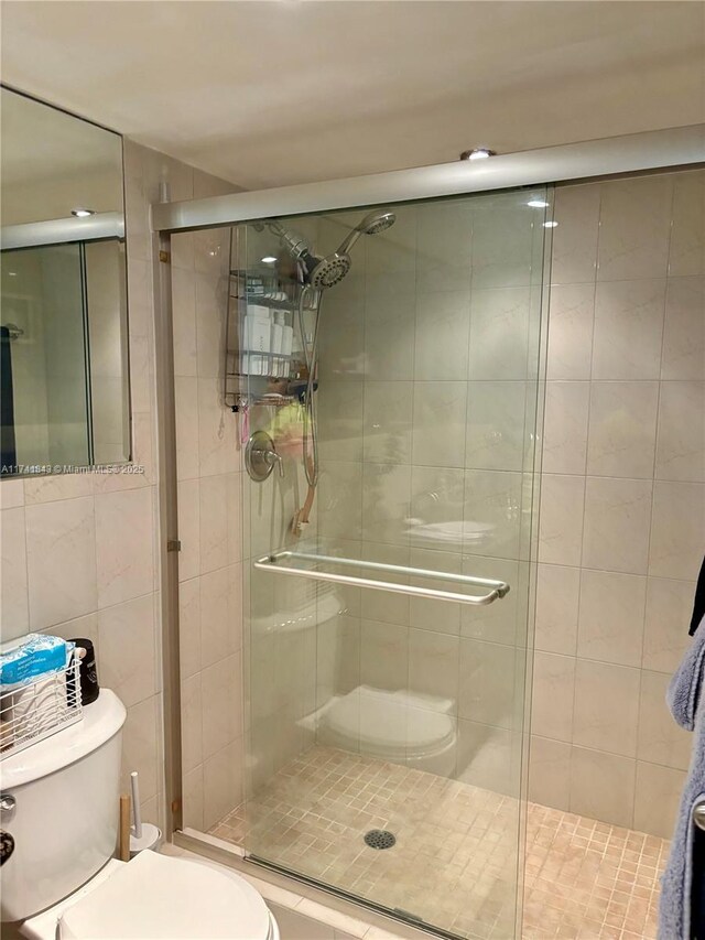 bathroom featuring a shower with door and toilet