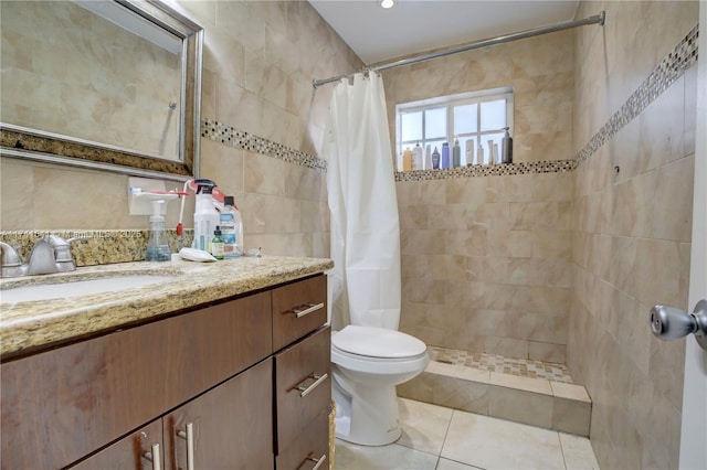 bathroom with tile walls, vanity, toilet, tile patterned floors, and a shower with curtain