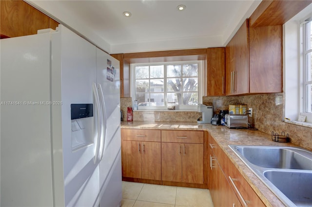 kitchen featuring tasteful backsplash, white refrigerator with ice dispenser, sink, and light tile patterned floors