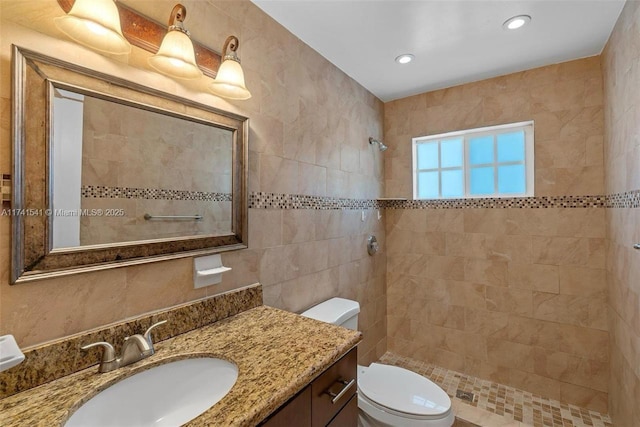 bathroom featuring vanity, tiled shower, tile walls, and toilet