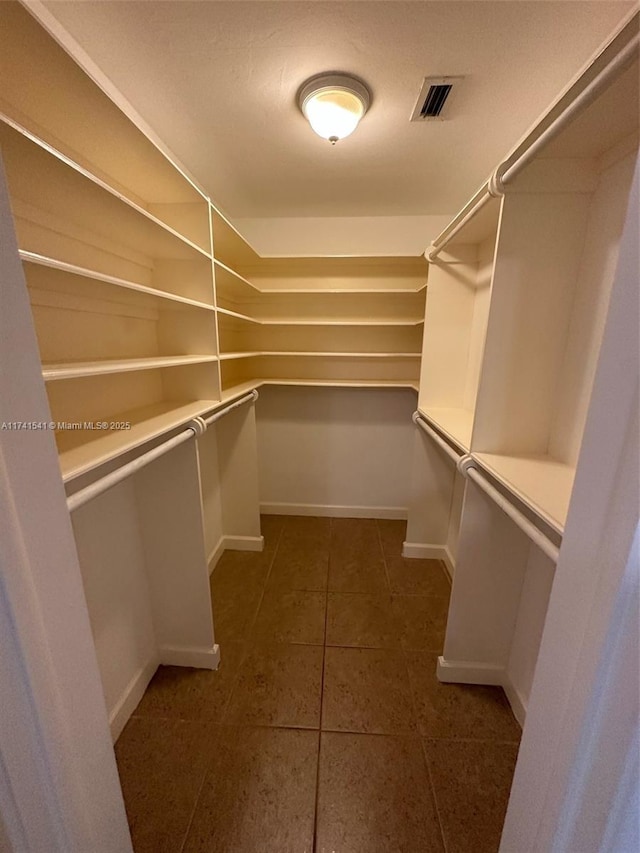 walk in closet with dark tile patterned floors