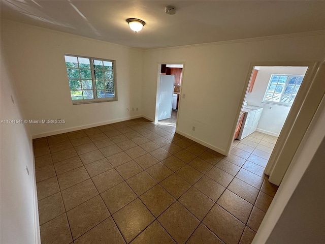 tiled spare room featuring crown molding, washer / dryer, and a healthy amount of sunlight