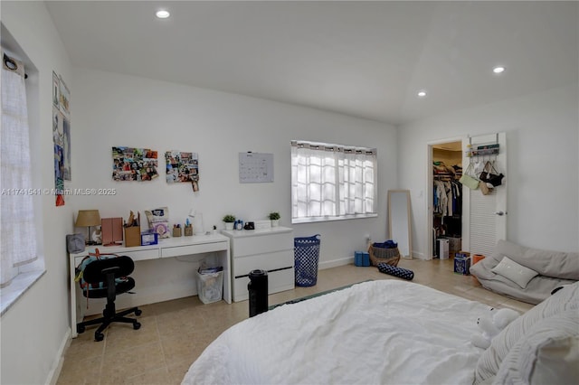 bedroom featuring light tile patterned floors, a spacious closet, and vaulted ceiling