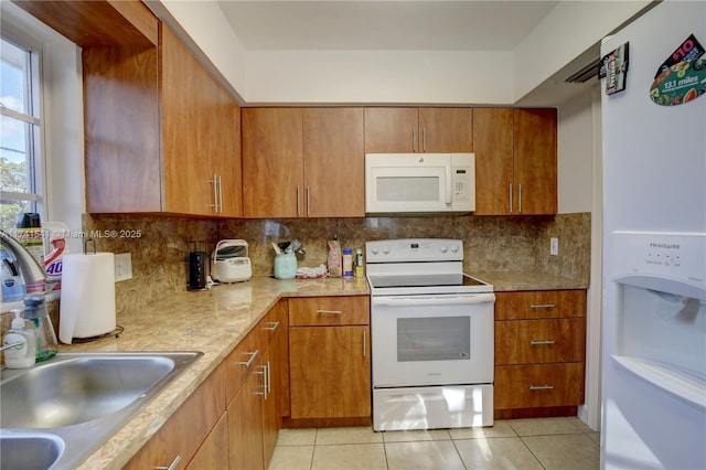 kitchen with sink, light tile patterned floors, white appliances, and decorative backsplash