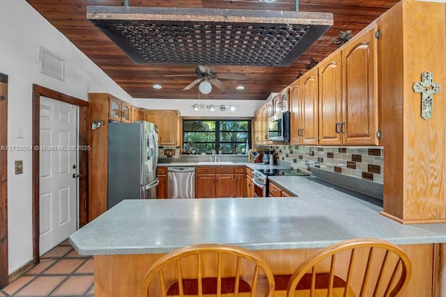 kitchen with sink, decorative backsplash, light tile patterned floors, kitchen peninsula, and stainless steel appliances