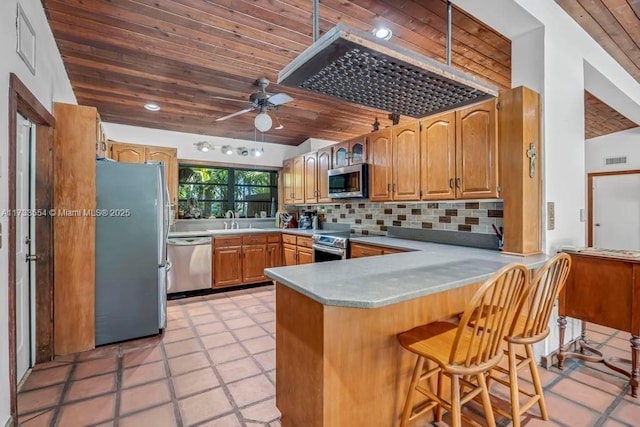 kitchen featuring a kitchen breakfast bar, kitchen peninsula, wooden ceiling, and appliances with stainless steel finishes