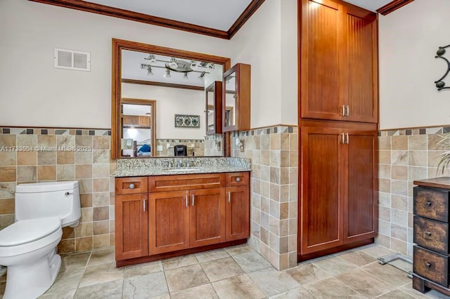 bathroom with tile walls, vanity, ornamental molding, toilet, and track lighting