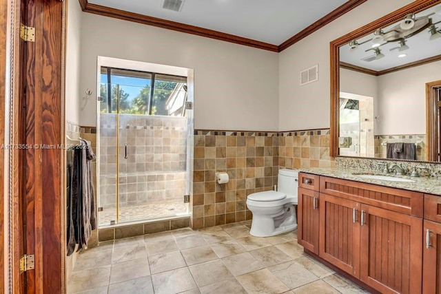 bathroom with toilet, a shower with shower door, crown molding, tile walls, and vanity